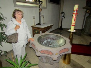 Gloria Temple stands at a baptismal font where her ancestors were baptized in Grosseneder, Germany