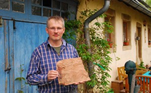 Roland Geiger holds a tile nearly 2,000 years old found in the parking lot of his home in St. Wendel, Germany.